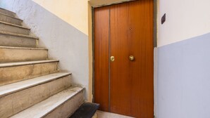 A wooden door with a brass handle, a set of concrete steps leading up to it, and a small landing area. - Murales Street on Spanish Quarter (Naples)