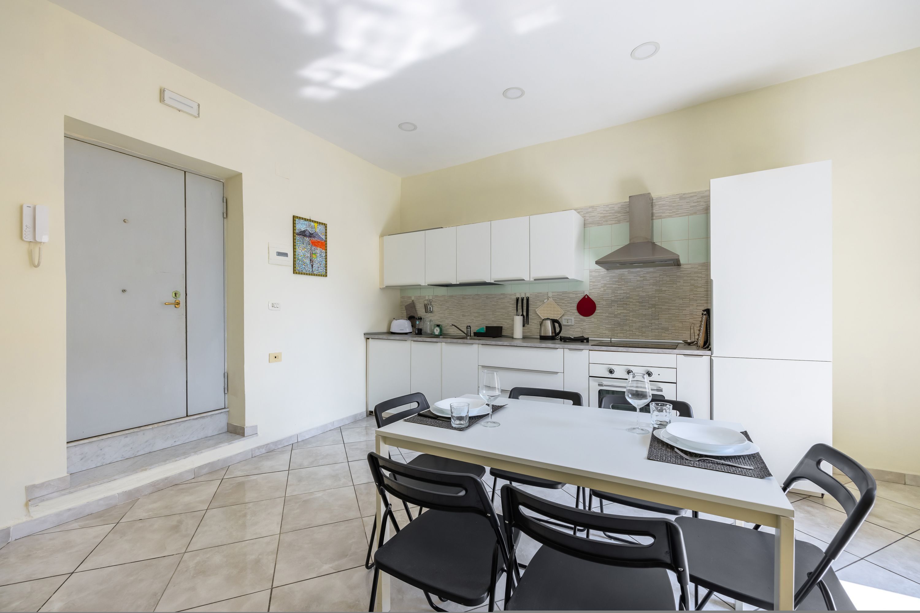 Une cuisine moderne avec des meubles blancs, une cuisinière et un coin repas comprenant une table et des chaises.