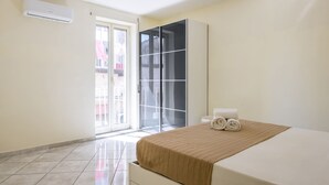 A hotel room with a bed, a wardrobe, a sliding glass door to the balcony, and an air conditioning unit. - Murales Street on Spanish Quarter (Naples)