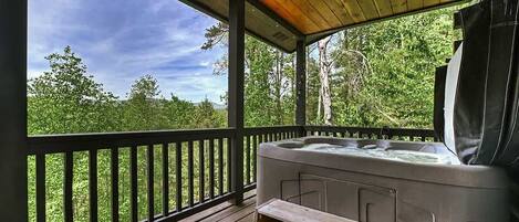 Un bain à remous sur une terrasse en bois, avec vue sur une forêt.