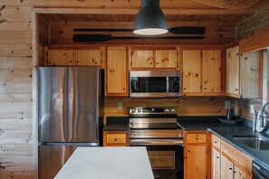Una cocina moderna con armarios de madera, electrodomésticos de acero inoxidable y una encimera negra.