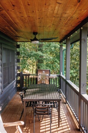 A covered outdoor patio with a table and chairs, a grill, and a ceiling fan. - Views @ Whitepath | Mtn Views + Hot Tub + Fire Pit (Ellijay)