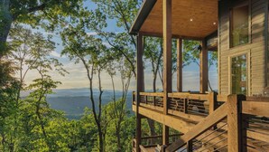 A wooden cabin with a balcony overlooking a forested landscape. - Big Abe | Sunset Views + Hot Tub + 6BR Lodge (Blue Ridge)