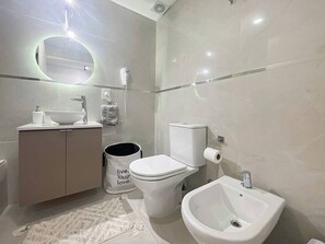 Ein modernes Badezimmer mit Toilette, Bidet, Waschbecken und Waschtisch.