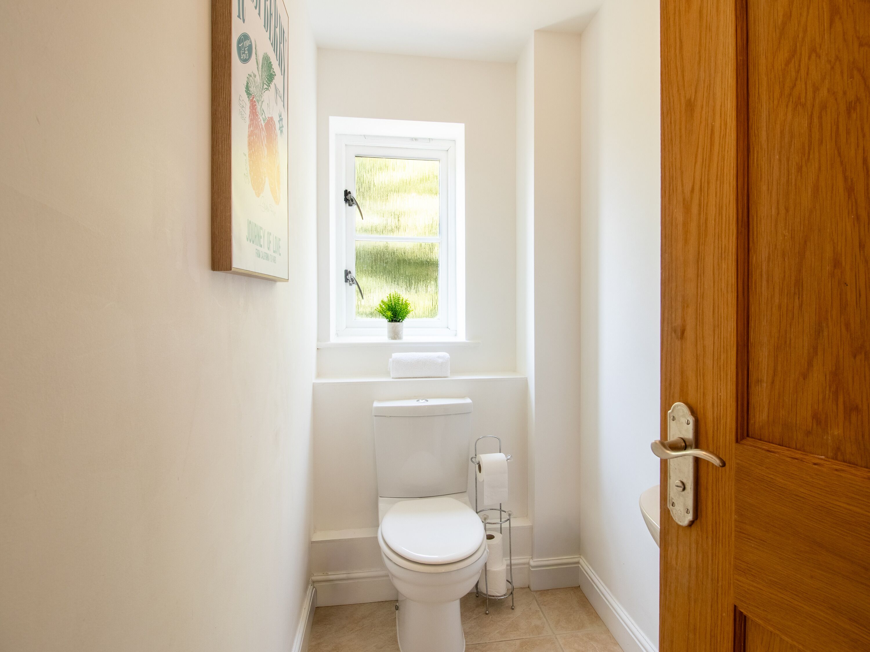 A small, clean bathroom with a toilet, a window, and a door.