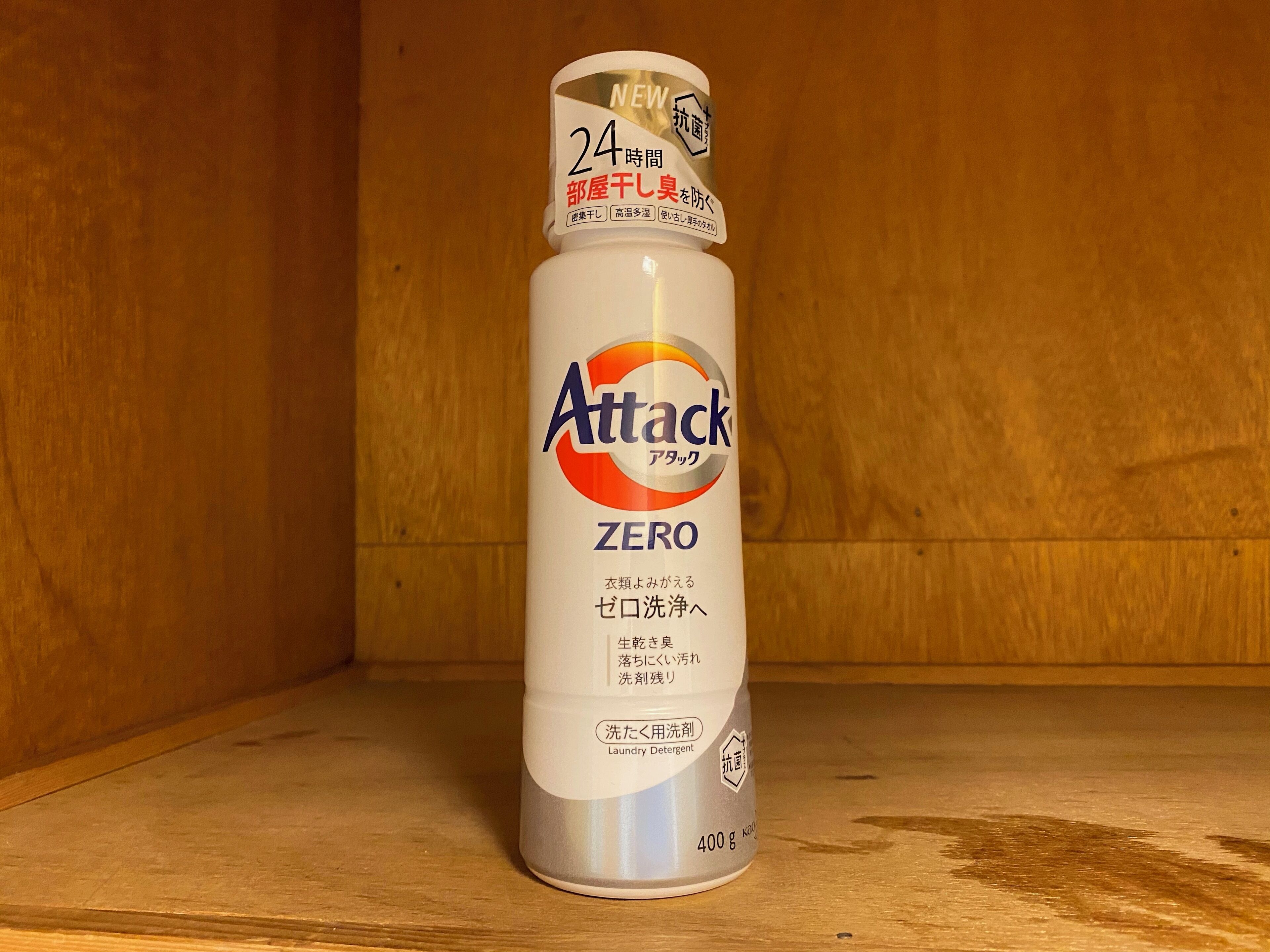 A bottle of Attack Zero laundry detergent on a wooden shelf.