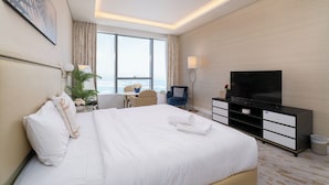 Een hotelkamer met een groot bed, een televisie, een bureau en uitzicht op de stad.