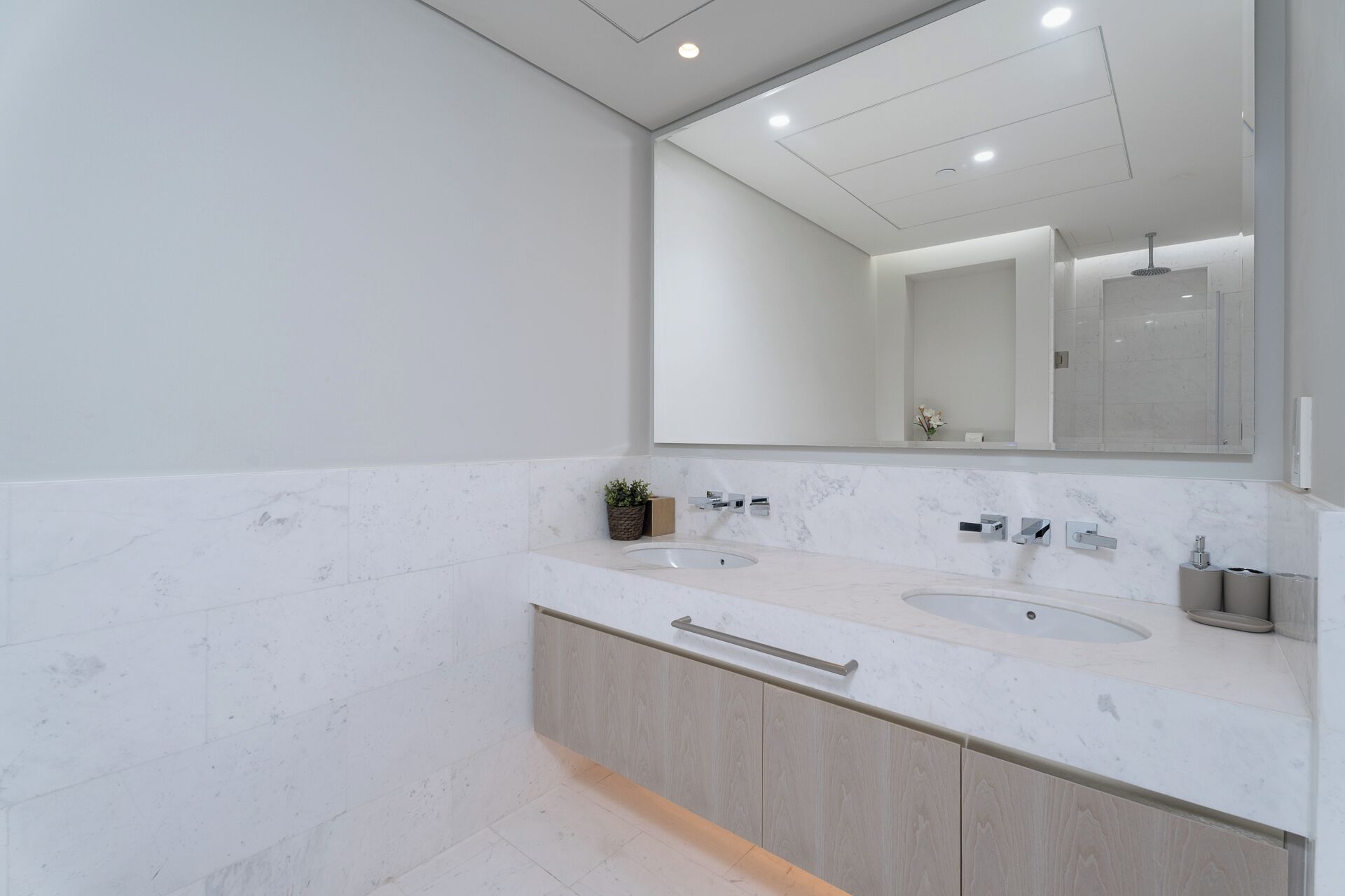 Un bagno moderno con due lavabi, uno specchio grande e un armadietto in legno.