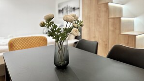 Ein modernes Hotelzimmer mit einem dunklen Holztisch, einer klaren Glasvase mit weißen Blumen und einer Wand mit Holzpaneelen.