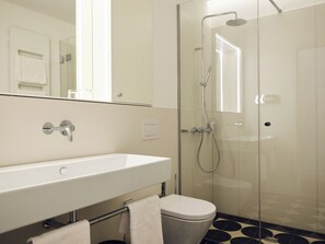 A modern bathroom with a glass shower enclosure, a white sink, and a toilet. - Hotel Lindenufer (Berlin)