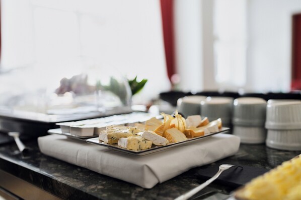 A cheese platter on a marble countertop with a napkin, a fork, and salt and pepper shakers. - Hotel Lindenufer (Berlin)
