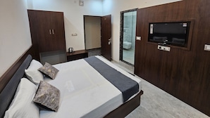 Ein modernes Schlafzimmer mit einem Bett, einem Holzschrank, einem an der Wand befestigten Fernseher und einem Deckenventilator.