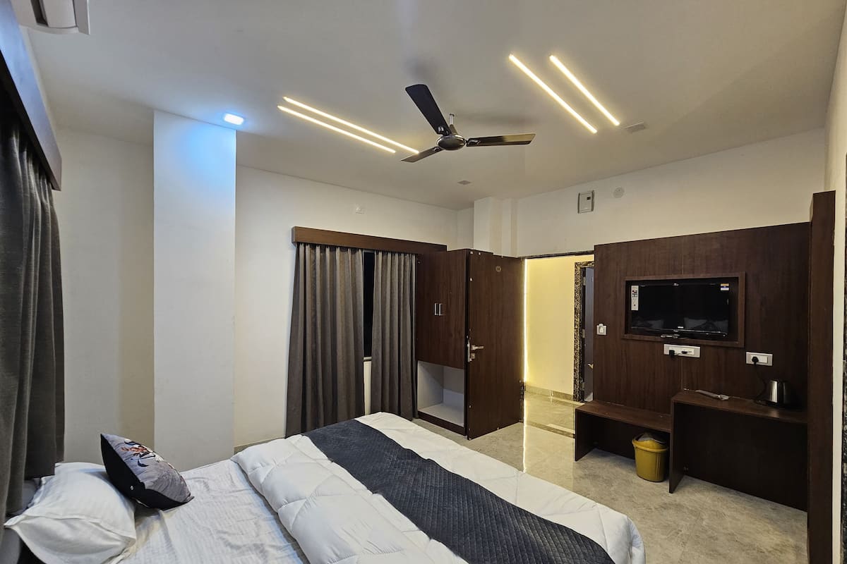 Une chambre d’hôtel équipée d’un lit, d’un ventilateur de plafond, d’un téléviseur fixé au mur et d’un bureau.