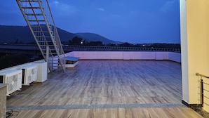 Eine Dachterrasse mit Holzboden, einer Metallleiter und Klimaanlagen.