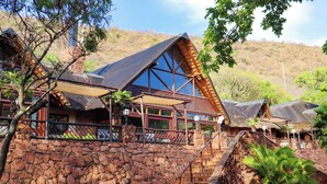 A rustic lodge with a stone wall, wooden balconies, and a thatched roof. - Olifants River Camping by Dream Resorts (Middelburg)