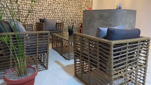 A room with wicker furniture, a stone wall, and a hanging light fixture. - Coral Castle (Goidhoo)