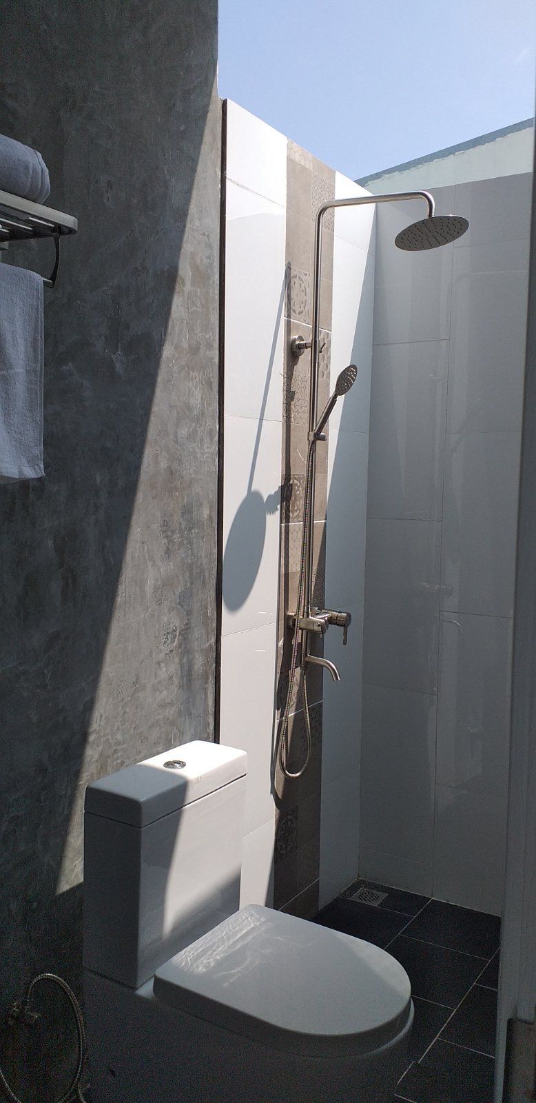 A modern bathroom with a shower, toilet, and towel rack.