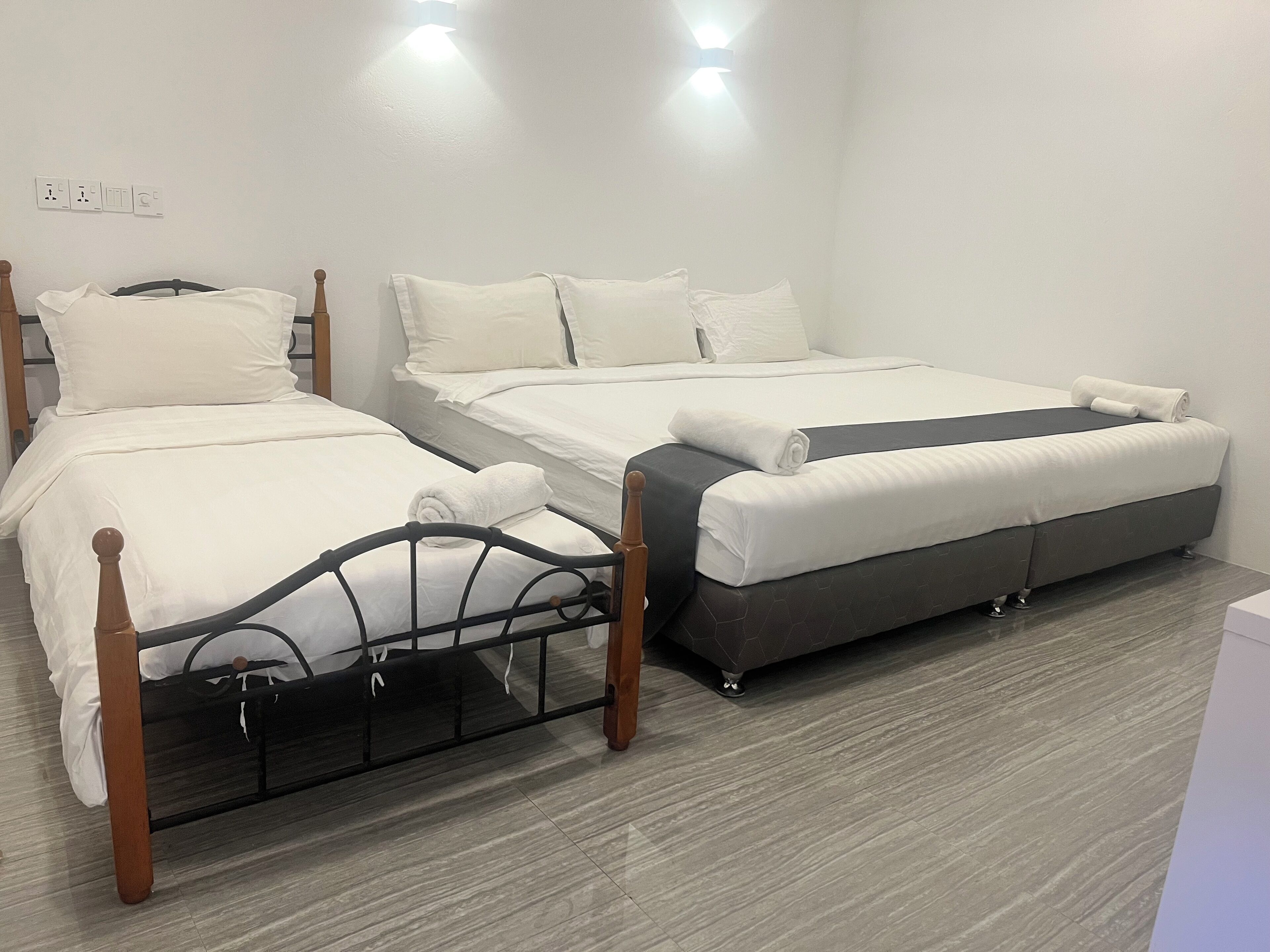 A hotel room with two beds, a wooden headboard, and a grey sofa.