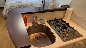 A compact kitchen with a gas stove, stainless steel sink, and a small countertop. - W312 Tokyo Monthly Rentals - Great Area Komazawa (Setagaya City)