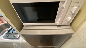 A compact kitchen with a built-in microwave and oven, a gas stove, and a small sink. - W311 Tokyo Monthly rental- Sakurashinmachi Sunrise (Setagaya City)