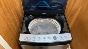 Vue de face d’un appareil combiné lave-linge et sèche-linge à chargement frontal, compact et en acier inoxydable, doté d’un panneau de commande numérique et d’un tambour transparent.
