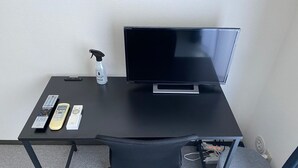 Un bureau noir avec un téléviseur à écran plat, un vaporisateur et des télécommandes.