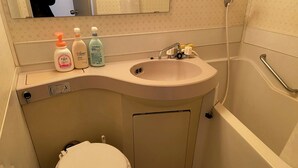 A bathroom with a toilet, sink, and bathtub. There are three bottles of hand soap on the sink counter. - W306 Monthly Rental Tokyo - Sunrise Living (Setagaya City)