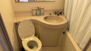 Une petite salle de bain avec des toilettes, un lavabo et une baignoire.