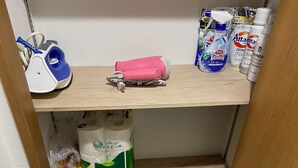 A shelf with a vacuum cleaner, a pink hairbrush, and various cleaning products. - W212 Tokyo Monthly Rental - Komazawa Telework (Setagaya City)
