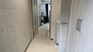 Un couloir avec un sol carrelé, un chambranle de porte en bois et une porte blanche.
