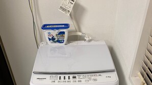A white Hisense washing machine with a control panel, a detergent dispenser, and a water inlet hose. - W201 Monthly Rental Tokyo - Large Studio (Setagaya City)