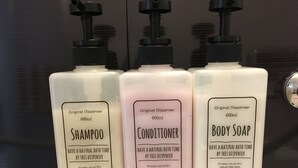 Three bottles of natural hair cosmetic products: shampoo, conditioner, and body soap, each with a pump dispenser. - W201 Monthly Rental Tokyo - Large Studio (Setagaya City)