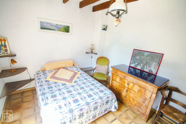 Un dormitorio con cama, cómoda, silla y ventilador de techo.