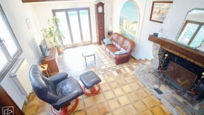 Un salón amplio con chimenea, mobiliario de cuero, un ventanal y vistas al exterior.
