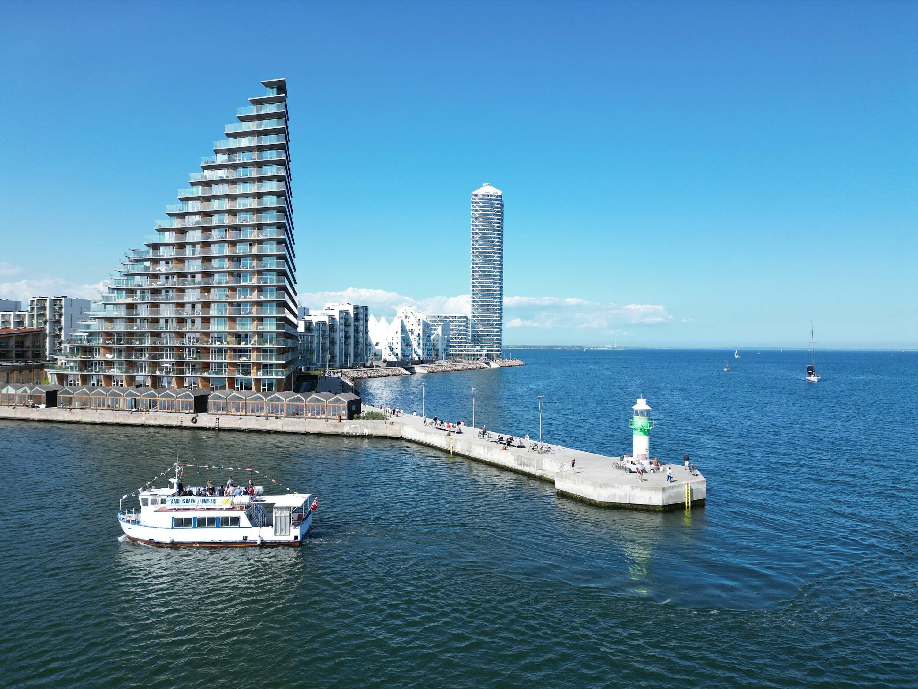 A waterfront cityscape with modern architecture, a pier, and a boat.