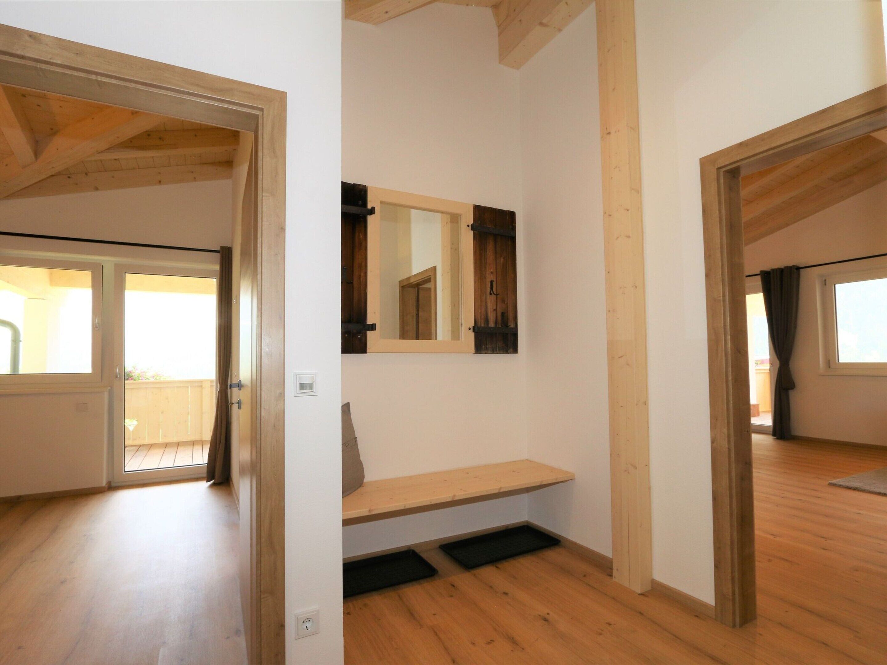 A room with wooden beams, a bench, a mirror, and a door leading to a balcony.