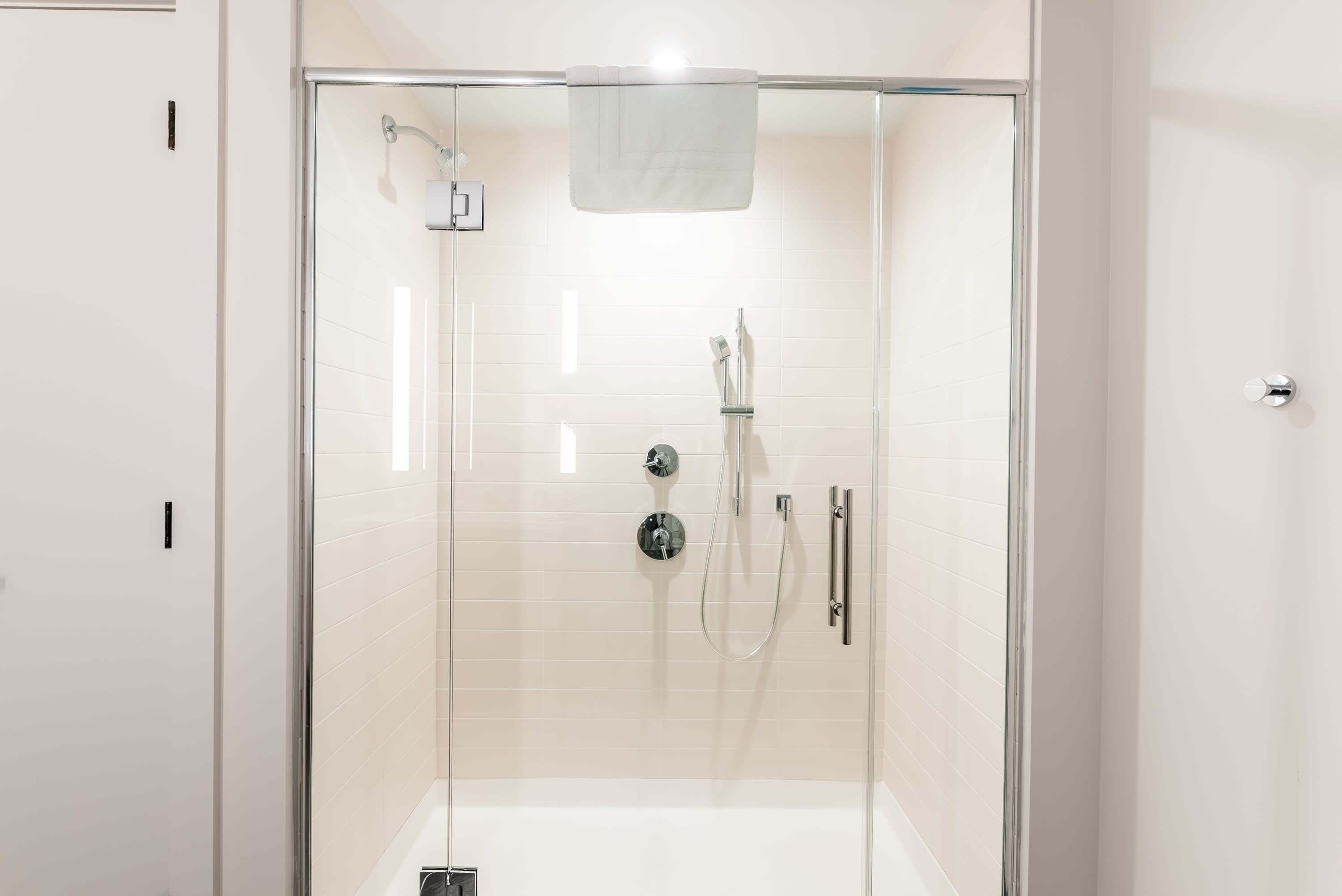 Eine moderne Dusche mit Glastür, Duschbrause und Handarmatur.