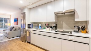 A modern kitchen with white cabinets, stainless steel appliances, and a grey countertop. - Modern Apt with Gym Near Restaurants (Boston, MA)