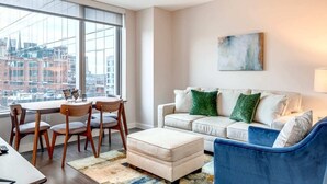 A modern living room with a dining area, large windows, and a city view.