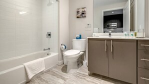 A modern bathroom with a bathtub, toilet, and vanity.