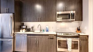 A modern kitchen with dark wood cabinets, stainless steel appliances, a microwave, and a stove.