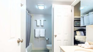 Une salle de bain avec des toilettes, une douche et un lavabo. Des serviettes sont accrochées au mur.