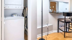 Une cuisine moderne dotée d’un lave-linge et d’un sèche-linge intégrés, d’un coin bar avec des tabourets et d’un grand lampadaire.