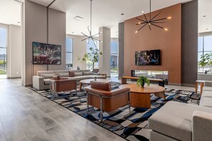 A spacious lobby with a sectional sofa, round coffee table, and a large painting.