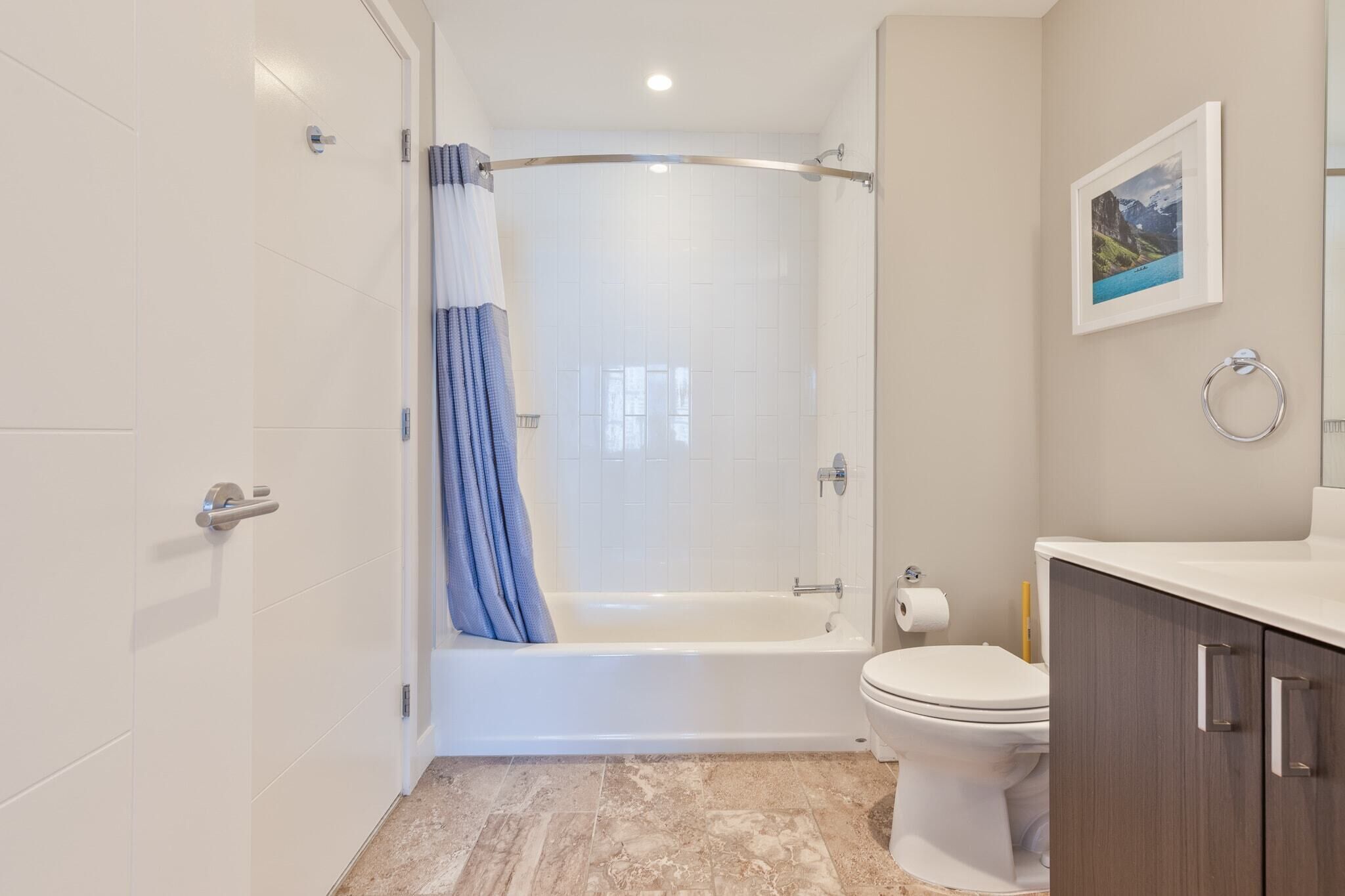 A modern bathroom with a bathtub, toilet, and vanity.