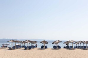 A beach with rows of sun loungers and thatched umbrellas. - Exclusive Beachfront Apartment (Potidea)