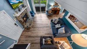 A spacious living area with a fireplace, a sofa set, and a dining area with a table and chairs.