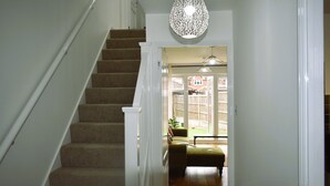 Un escalier menant à un espace de vie agrémenté d’un luminaire suspendu et offrant une vue sur l’extérieur.