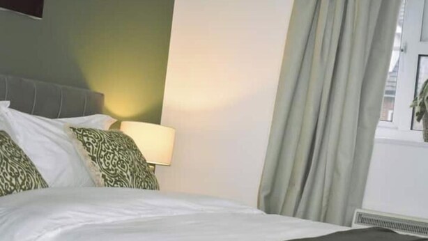Une chambre d’hôtel avec un lit, une lampe et une fenêtre avec des rideaux.