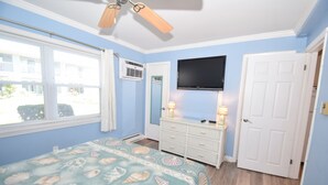 A bedroom with a bed, a dresser, a television, and a door. - Virginian 4-Oceanside 11th St, Free WiFi, W/D, AC (Ocean City)